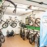 Fahrradgarage Krumbacherhof, © Wiener Alpen/Martin Fülöp Innenansicht einer Fahrradgarage mit mehreren aufgehängten und stehenden Fahrrädern sowie einem blauen Banner der Wiener Alpen Rad-Gastgeber.
