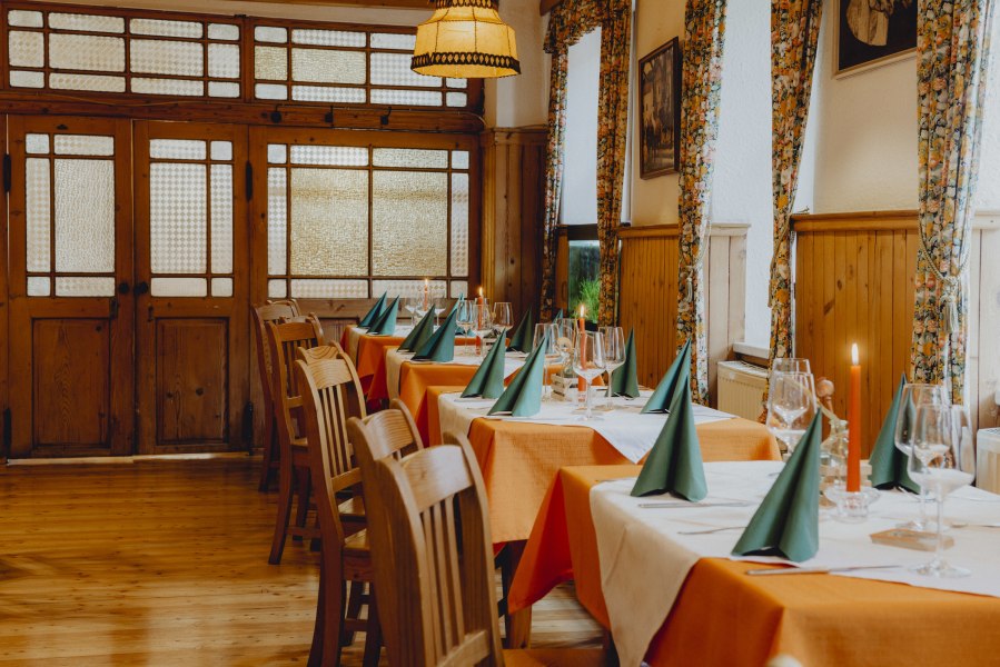 Einkehren und Platz nehmen, © Niederösterreich Werbung/Rita Newman Ein Koch in schwarzer Uniform kocht in einer professionellen Küche mit mehreren Töpfen und Kellen an der Wand.