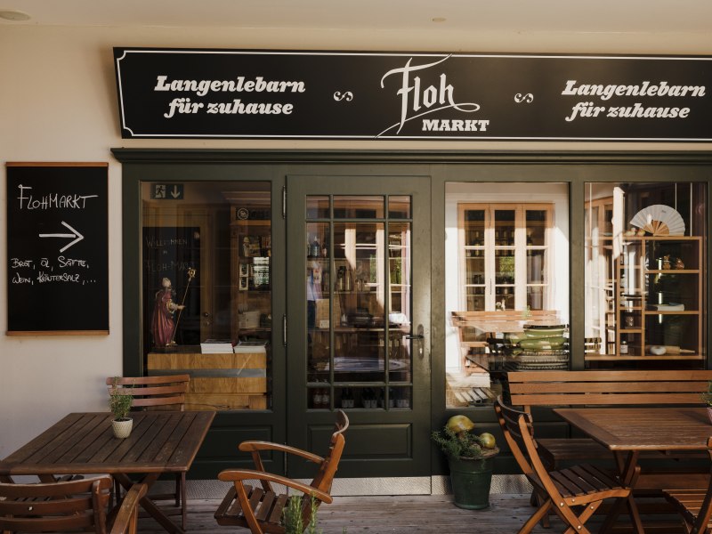 Wirtshaus mit regionalem Flohmarkt, © Niederösterreich Werbung/Michael Reidinger Eingang zu einem regionalen Laden mit Schildern, Holztischen und Stühlen.