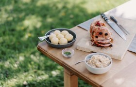 Mostbratl mit Dörrpflaumen gespickt, © Niederösterreich Werbung/Julius Hirtzberger Mostbratl mit Dörrpflaumen auf einem Tisch im Freien serviert.