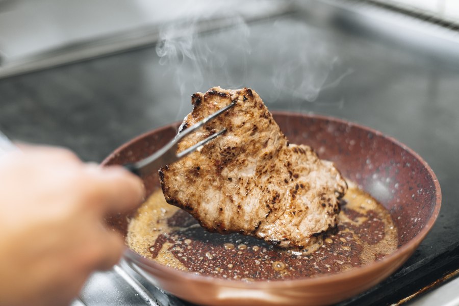 Abwechslungsreiche Spezialitätenwochen, © Niederösterreich Werbung/David Schreiber Ein Stück Fleisch wird in einer Pfanne gebraten.
