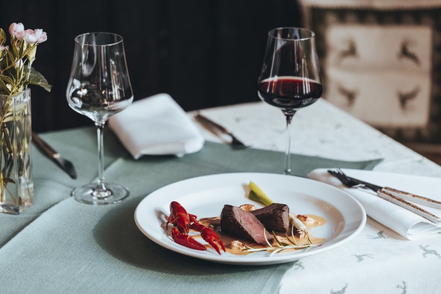 Erfrischend anders: Reh trifft Flusskrebs, © Niederösterreich Werbung/David Schreiber Elegantes Abendessen mit Fleisch, Flusskrebs und Rotwein auf gedecktem Tisch.