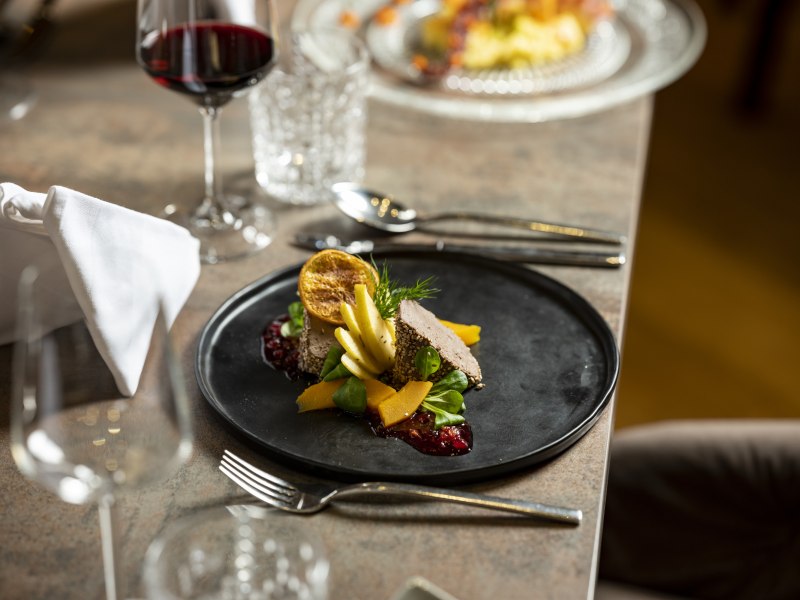Geflügelleber Pastete, © Niederösterreich Werbung/Michael Reidinger Elegantes Gericht auf schwarzem Teller mit Rotwein im Hintergrund.