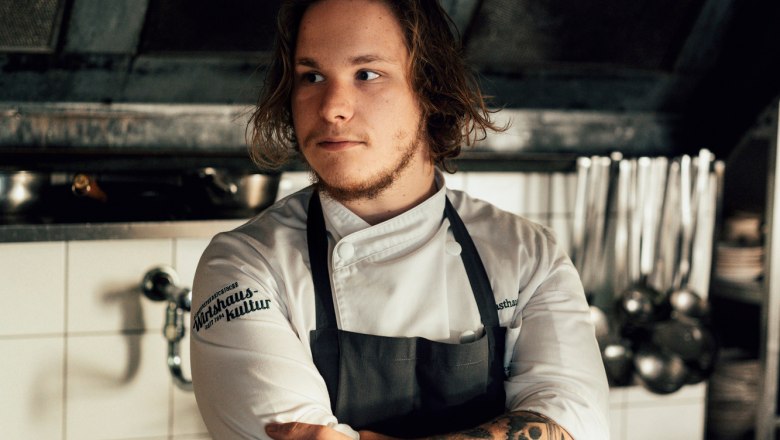 Laurent Amon hat das Zepter von Ulli Amon-Jell übernommen, © Niederösterreich Werbung/Julius Hirtzberger Junger Koch mit Tattoos in einer professionellen Küche, nachdenklich blickend.