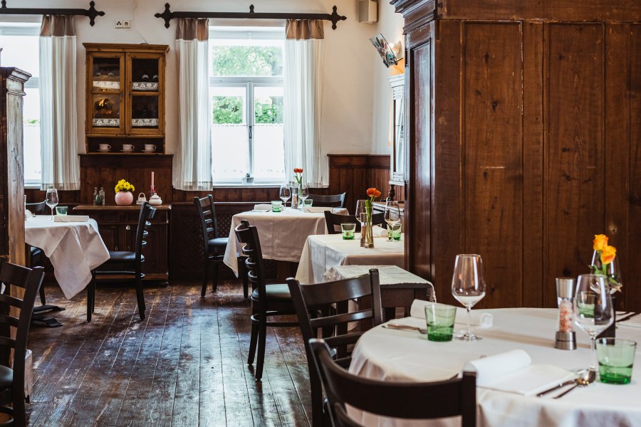 Ein Wirtshaus, wo die Leute zusammenkommen, © Niederösterreich Werbung/David Schreiber Gemütliches Wirtshaus mit Holzmöbeln und gedeckten Tischen.
