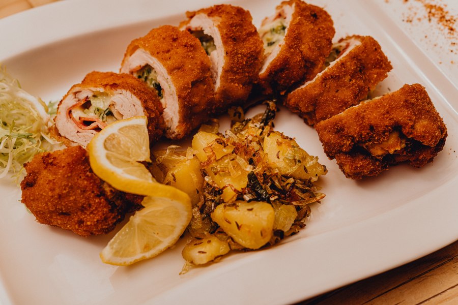 Gefülltes gebackenes Putenfilet, © Niederösterreich Werbung/Klaus Engelmayer Gefülltes gebackenes Putenfilet mit Kartoffelbeilage und Zitronenscheiben auf einem weißen Teller.