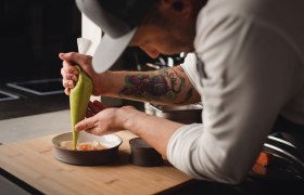 Hier entsteht nachhaltig Großes, © Niederösterreich Werbung/Daniela Führer Ein Koch dekoriert ein Gericht mit einer grünen Sauce aus einem Spritzbeutel.
