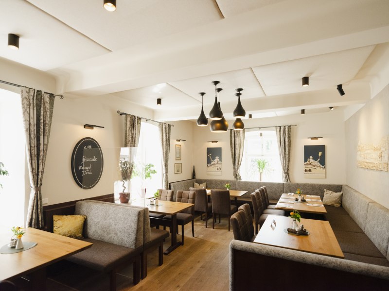 Bauhistorik trifft auf modernes Ambiente, © Niederösterreich Werbung/Michael Reidinger Modernes Restaurant mit Holztischen, grauen Polsterbänken und stilvollen Lampen.