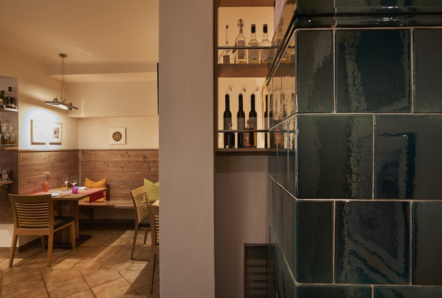 Extra gemütliche Stube mit Kachelofen, © Niederösterreich Werbung/Andreas Hofer Gemütliche Stube mit Holzmöbeln, Kachelofen und Flaschenregal.