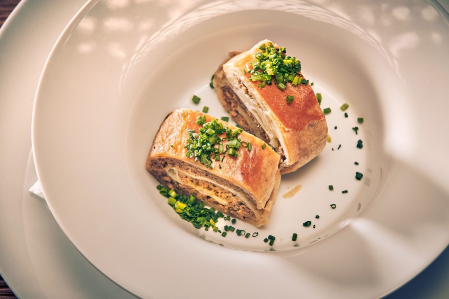 Traditioneller Fleischstrudel, © Niederösterreich Werbung/Andreas Hofer Zwei Stücke Fleischstrudel mit Schnittlauch auf weißem Teller serviert.