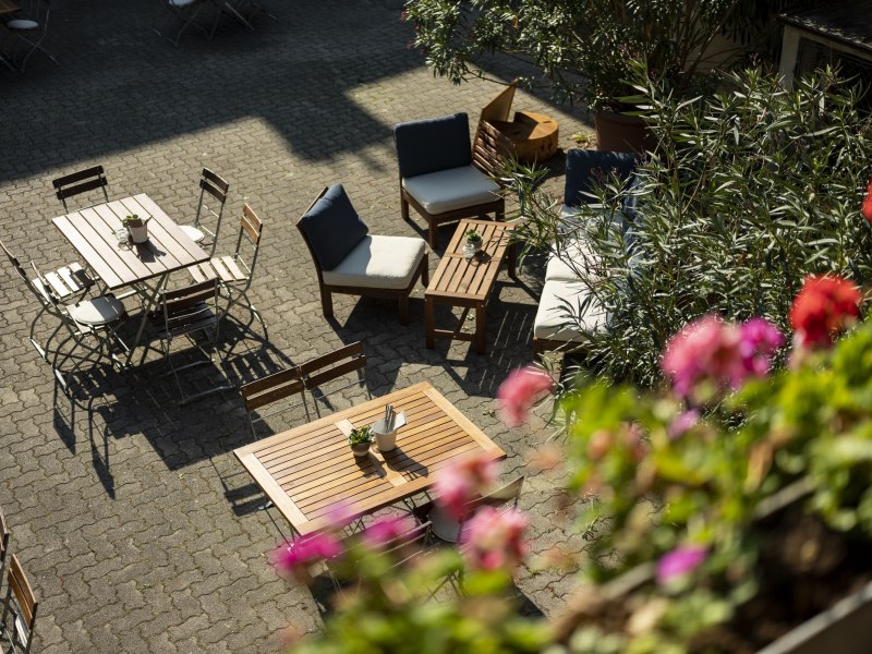 Gastgarten im Innenhof, © Niederösterreich Werbung/Michael Reidinger Gemütlicher Innenhof mit Holzmöbeln und blühenden Pflanzen.