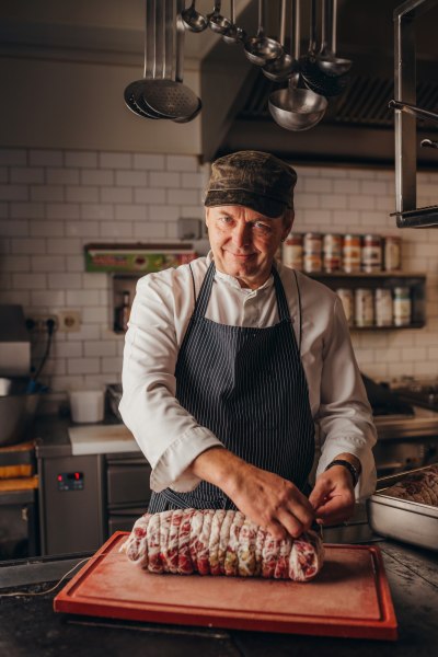 Koch Hubert Grubner, © Niederösterreich Werbung/Daniela Führer Ein Koch in einer Küche bindet ein großes Stück Fleisch mit Küchengarn.