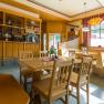 Gemütliches Gastzimmer, © Wiener Alpen- Kremsl Gemütliches Gastzimmer mit Holzmöbeln, Tischen und Stühlen, dekoriert mit Blumen und Vorhängen, sonnendurchflutet durch große Fenster.
