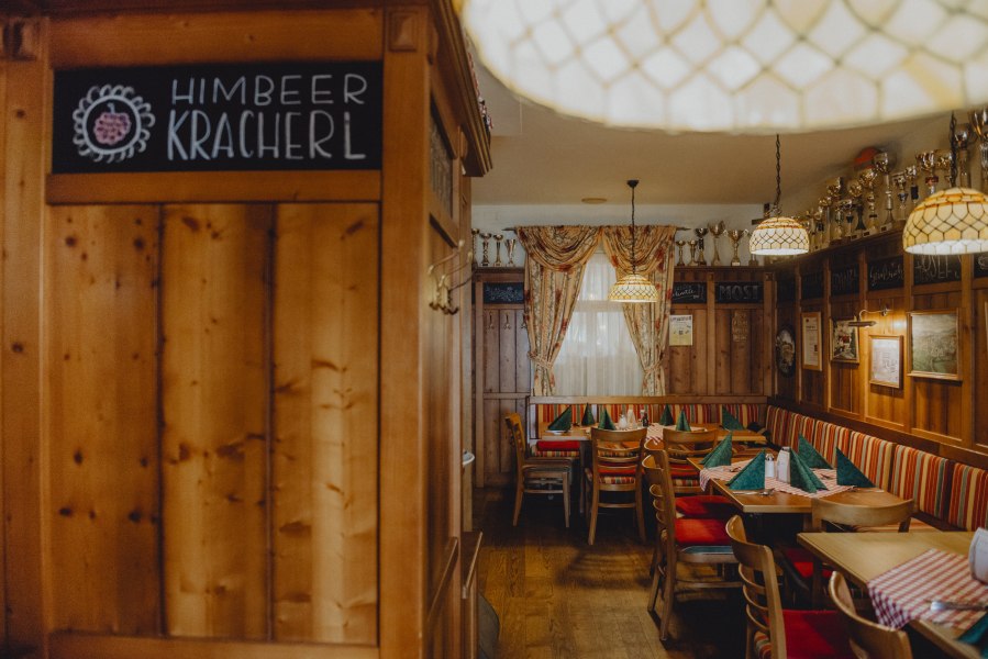 Urige Bauernstube, © Niederösterreich Werbung/Rita Newman Gemütliche Bauernstube mit Holzmöbeln, karierten Tischdecken und Pokalen auf einem Regal.