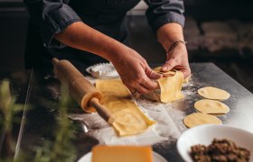 Selbstgemachte Teigwaren, © Niederösterreich Werbung/Daniela Führer Person formt Teigtaschen auf bemehlter Arbeitsfläche.