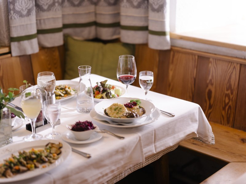 Wildspezialitäten, vegetarische Gerichte, © Niederösterreich Werbung/Julius Hirtzberger Ein gedeckter Tisch mit verschiedenen Gerichten und Getränken in einem gemütlichen Restaurant.