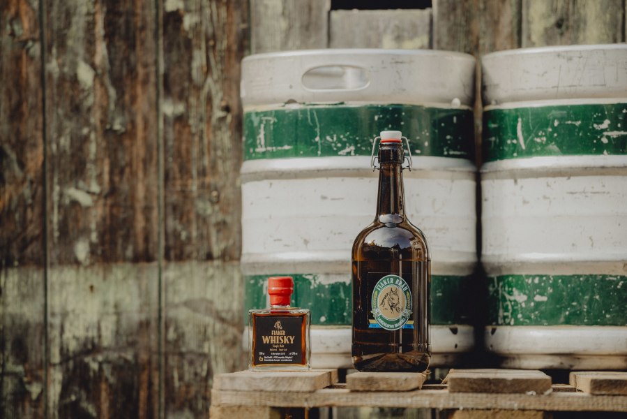 Fiakerbräu, Whisky „Single Malt“, © Niederösterreich Werbung/Rita Newman Flasche Fiakerbräu und Fiaker Whisky vor Holzfass.