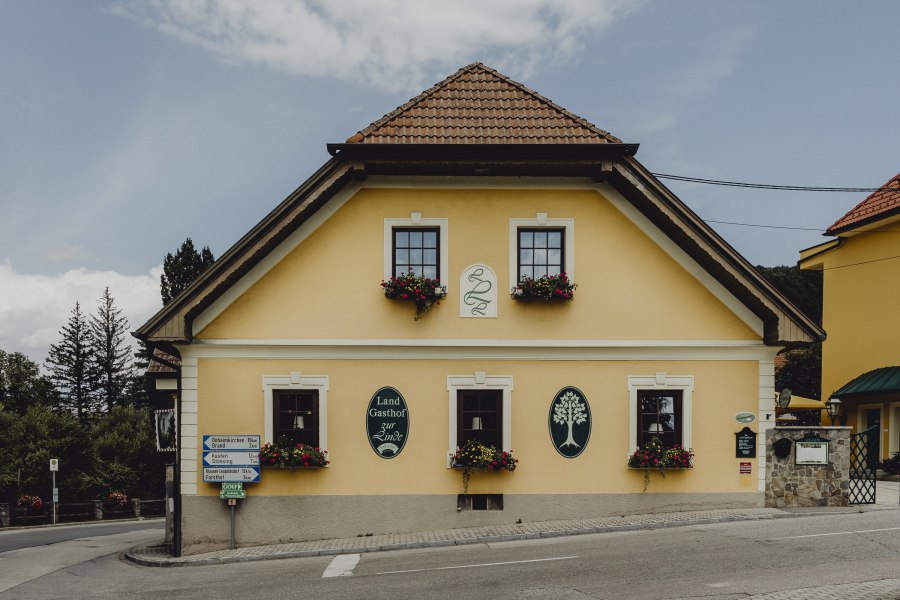 Steaks in Reifeschränken, © Niederösterreich Werbung/Sophie Menegaldo Gelbes Gasthaus mit Blumenkästen und Schildern an der Fassade.
