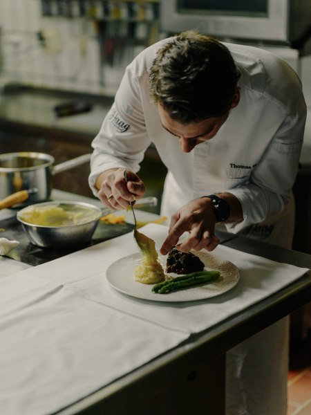 Thomas Haag zaubert in der Küche, © Niederösterreich Werbung/Julius Hirtzberger Ein Koch richtet ein Gericht mit Spargel und Kartoffelpüree auf einem Teller an.