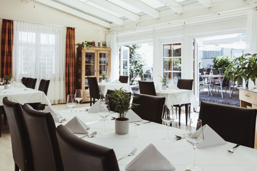 Gelebte wilde Wirtshauskultur, © Niederösterreich Werbung/David Schreiber Elegantes Restaurant mit weißen Tischdecken und Glasfront zur Terrasse.