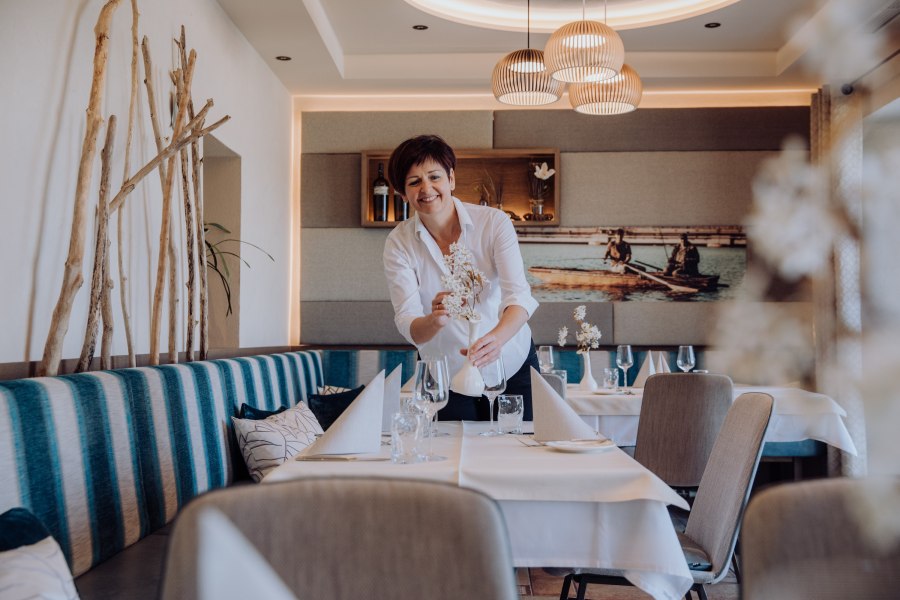 Wirtin Anneliese Harthaller kennt die Wünsche der Gäste, © Niederösterreich Werbung/thecreatingclick.com Eine Frau in einem Restaurant arrangiert Blumen auf einem Tisch.