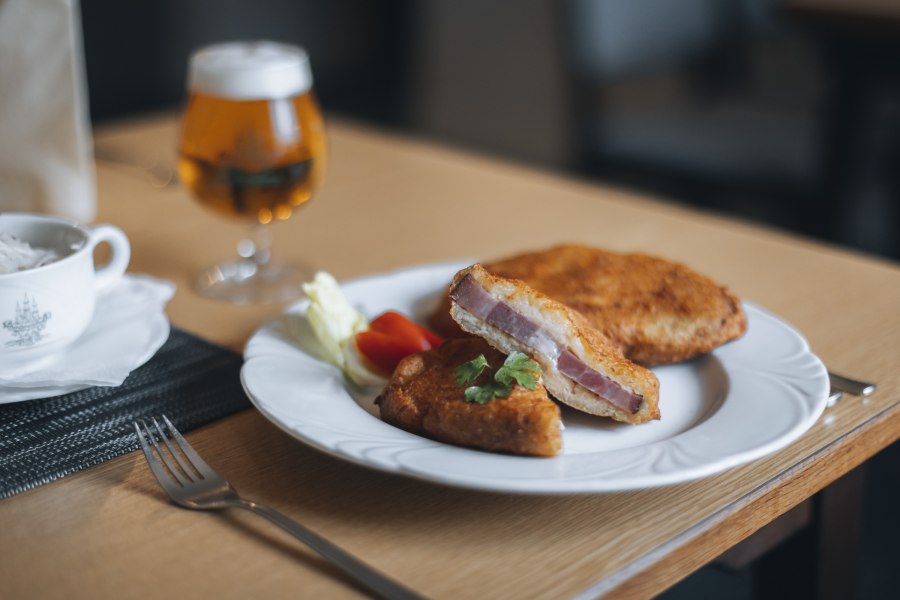 Schweinsschopf im Erdäpfelmantel, © Niederösterreich Werbung/David Schreiber Ein Teller mit Schweinsschopf im Erdäpfelmantel, serviert mit Salat und einem Glas Bier im Hintergrund.