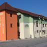 Haus, © Peter Pichler Ein Gasthof mit orangefarbenem Turm und grün-weißer Fassade an einer Straße.