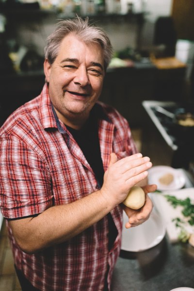 Wirt Christian Vlasaty, © Niederösterreich Werbung/Mara Hohla Ein Mann in kariertem Hemd formt Knödel in einer Küche.