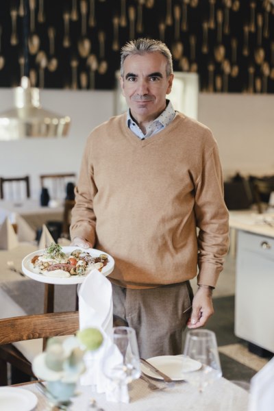 Wirt und Sommelier Martin Blauensteiner, © Niederösterreich Werbung/David Schreiber Ein Mann in einem Restaurant hält einen Teller mit Essen in der Hand.