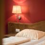 Doppelzimmer, © Wiener Alpen- Kremsl Ein gemütliches Doppelzimmer mit Holzkopfteil, roter Wand und Wandlampe.