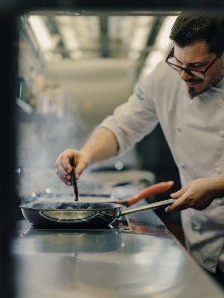Wirt und Chefkoch Markus Stadler, © Niederösterreich Werbung/Julius Hirtzberger Ein Koch in weißer Uniform brät etwas in einer Pfanne in einer professionellen Küche.