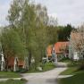 Theater- und Feriendorf Königsleitn, © Theater- und Feriendorf Königsleitn Ein Dorf mit roten Dächern und blühenden Bäumen im Frühling.