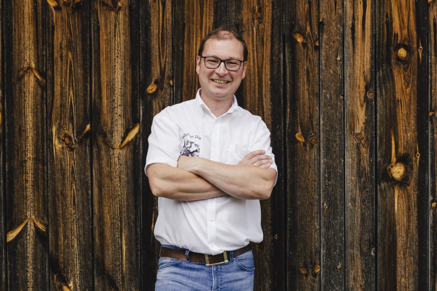 Wirt Reinhard Lang, © Niederösterreich Werbung/David Schreiber Mann in weißem Hemd vor Holzwand.