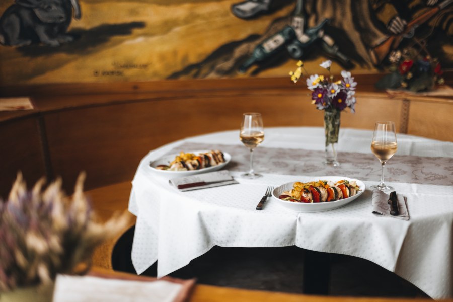 Wirtshaus ist bekannt für Wildspezialitäten, © Niederösterreich Werbung/David Schreiber Gedeckter Tisch in einem Wirtshaus mit zwei Tellern und Weingläsern.