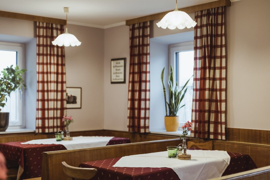 Einladende Wirtshausstube, © Niederösterreich Werbung/David Schreiber Gemütliche Wirtshausstube mit Holzmöbeln, karierten Vorhängen und dekorierten Tischen.