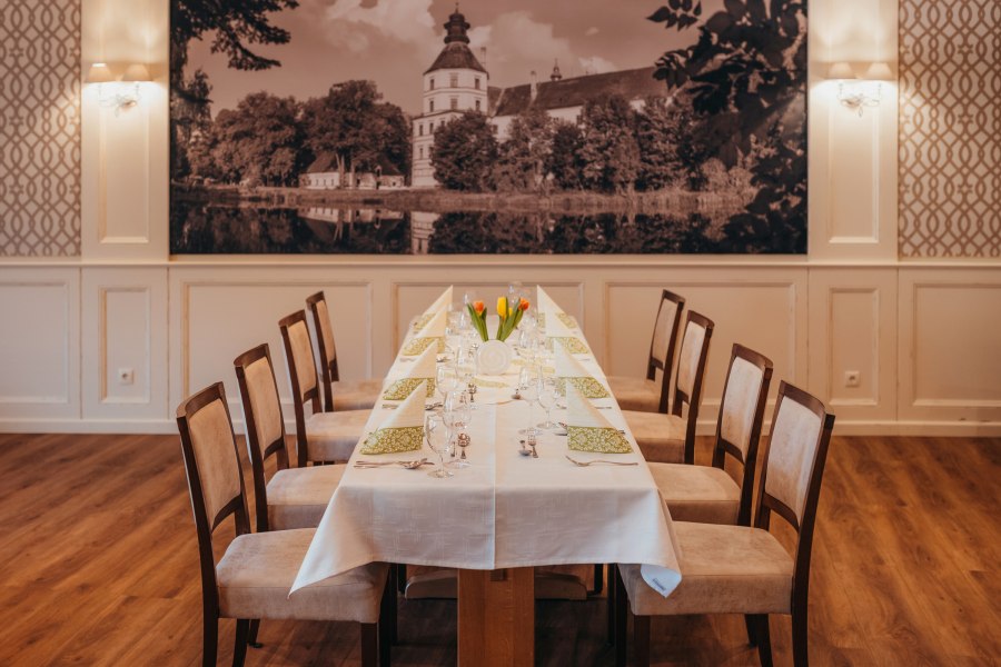 Schloss-Saal, © Niederösterreich Werbung/Daniela Führer Eleganter Speisesaal mit langem Tisch, gedeckt mit weißen Tischdecken und grünen Servietten, im Hintergrund ein großes Schlossbild.
