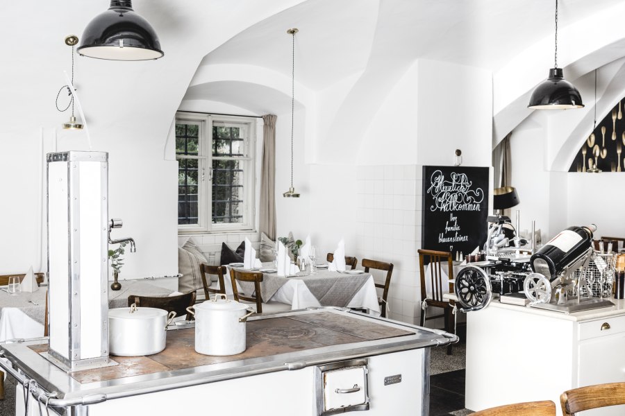 Helles Interieur sorgt für Gemütlichkeit, © Niederösterreich Werbung/David Schreiber Helles Restaurantinterieur mit weißen Wänden, Holzmöbeln und einem alten Herd.