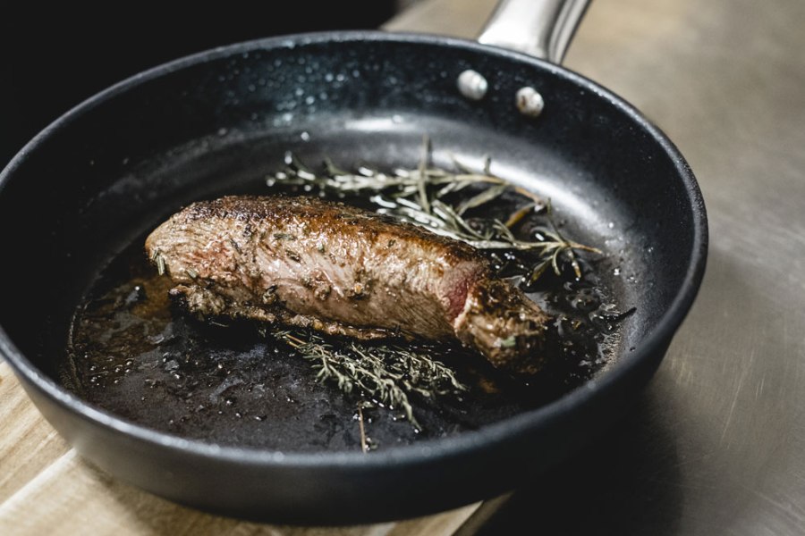 Wild aus eigener Jagd, © Niederösterreich Werbung/David Schreiber Gebratenes Fleischstück mit Kräutern in einer Pfanne.