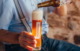 Selbstgebrautes Bier, © Niederösterreich Werbung/Daniela Führer Eine Person schenkt Bier aus einer Flasche in ein Glas mit der Aufschrift 'HaselBräu'.