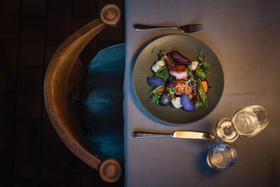 Schweinsmedaillons, Zwiebel-Most-Sauce, lila Erdäpfel, © Niederösterreich Werbung/Daniela Führer Ein Teller mit Schweinsmedaillons, lila Kartoffeln und Gemüse auf einem gedeckten Tisch.