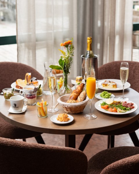 Genuss am Morgen, © thefirstthought Ein gedeckter Frühstückstisch mit verschiedenen Speisen, Getränken und Blumen.