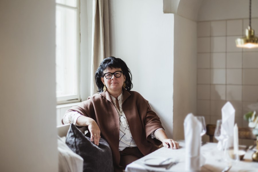 Wirtin Sandra Blauensteiner, © Niederösterreich Werbung/David Schreiber Frau sitzt an einem gedeckten Tisch in einem gemütlichen Raum.