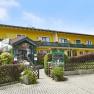 Krumbacherhof, © Wiener Alpen / Bene Croy Gelbes Gebäude mit Balkon und Blumen, Krumbacherhof, Eingang mit Vordach und Schildern.