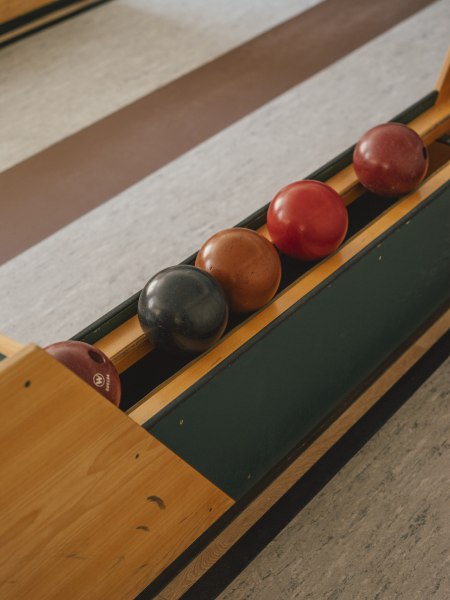 Kegelbahn und Streichelzoo, © Niederösterreich Werbung/Julius Hirtzberger Kegelbahn mit vier Kegelkugeln in einer Holzhalterung.