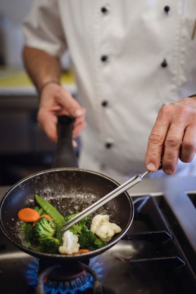 Haubenküche an der Moststraße, © Niederösterreich Werbung/Daniela Führer Ein Koch in weißer Uniform brät Gemüse in einer Pfanne auf einem Gasherd.