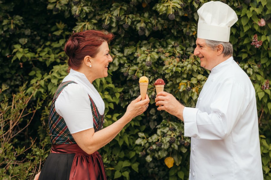 Eis, Teigwaren, Chutneys – alles von Hand gemacht, © Niederösterreich Werbung/Daniela Führer Zwei Personen halten Eistüten und lächeln sich an, vor einem Hintergrund aus grünen Blättern.