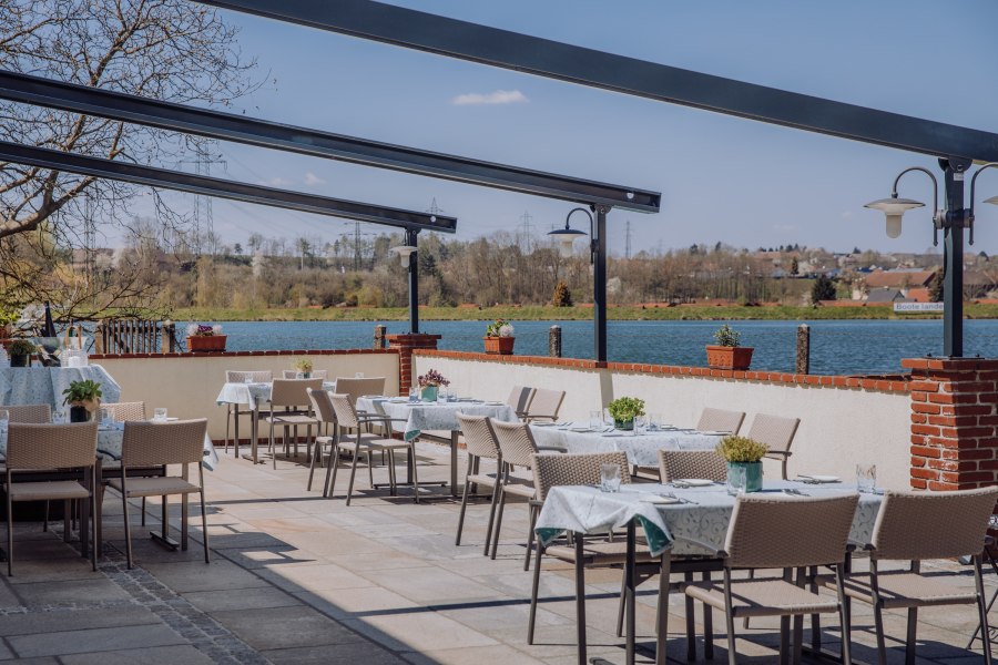 Terrasse mit Blick auf den Stausee, © Niederösterreich Werbung/thecreatingclick.com Terrasse mit Tischen und Stühlen, Blick auf einen Stausee und umliegende Landschaft.