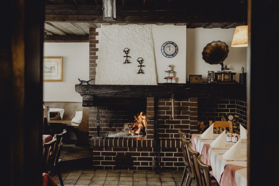 Einkehren in Oberkirchbach, © Niederösterreich Werbung/Sophie Menegaldo Gemütliches Restaurant mit Kamin, rustikaler Einrichtung und gedecktem Tisch.