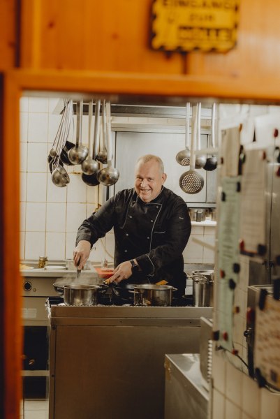 Chefkoch Jörg Hartl, © Niederösterreich Werbung/Rita Newman Ein Teller mit Fiakergulasch und ein Glas Bier auf einem Holztisch.