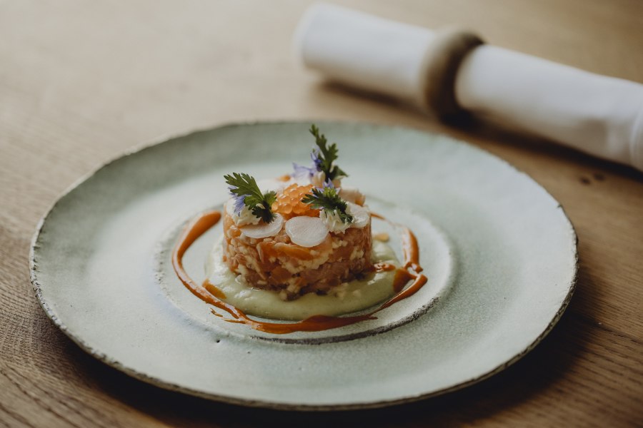 Steaks in Reifeschränken, © Niederösterreich Werbung/Sophie Menegaldo Gourmetgericht auf einem Teller mit Lachs, Kräutern und Soße dekoriert.